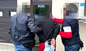 zatrzymany mężczyzna w asyście dwóch nieumundurowanych policjantów