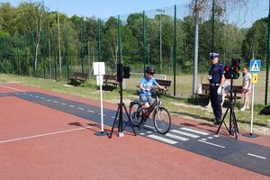 sygnalizatory świetlne, umundurowany policjant oraz uczeń na rowerze zdający egzamin