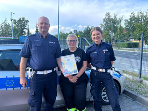 policjanci piaseczyńskiej drogówki wspólnie z przedstawicielką ochotnicznej straży pożarnej, która trzyma dyplom z podziękowaniem