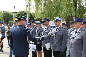 Umundurowany policjant składa gratulacje innemu umundurowanemu policjantowi.