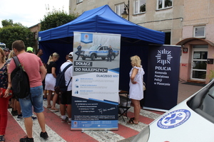 Na zdjęciu widać namiot a przed nim stoi kilka osób i baner z napisem zostań stołecznym policjantem