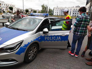 Na zdjęciu jest policyjny radiowóz do którego wsiada młodzież.