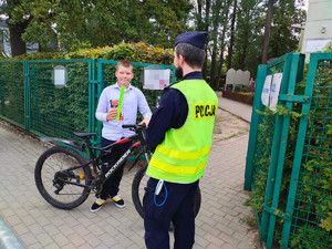 umundurowany policjant i dziecko z odblaskiem w ręku