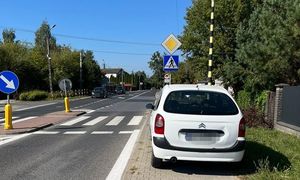 białe auto marki renault zaparkowane na całej szerokości chodnika, bezpośrednio przed przejściem dla pieszych