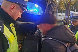 rowerzysta w trakcie badania alkomatem, obok policjanci