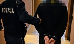 zatrzymany mężczyzna z kajdankami na rękach w asyście policjanta