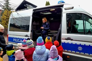 policjantka wydziału ruchu drogowego w trakcie spotkania z dziećmi, pokazuje dzieciom radiowóz