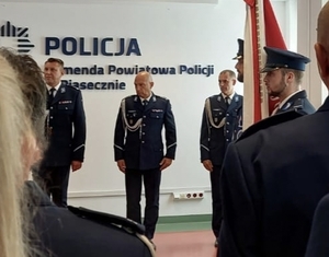 Na zdjęciu widać umundurowanych policjantów ma tle napisu Policja. Komenda Powiatowa Policji w Piasecznie.