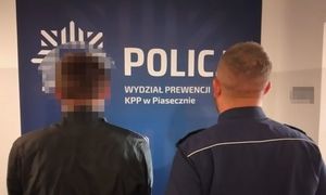 zatrzymany mężczyzna z umundurowanym policjantem, w tle napis KPP Piaseczno Wydział Prewencji