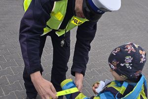 policjant dający dziecku odblask