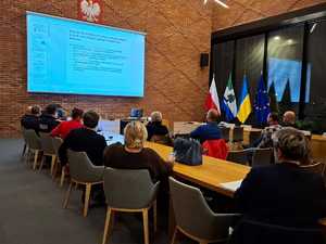 mieszkańcy siedzący na sali konferencyjnej, w tle prezentacja