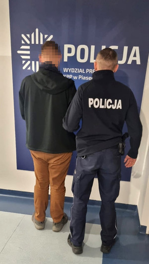 umundurowany policjant z zatrzymanym mężczyzną