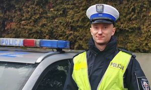 Piotr Dykciński stojący obok oznakowanego radiowozu