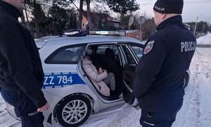 policjanci stojący przy radiowozie w którym siedzi odnaleziona kobieta