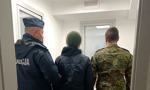 zatrzymany mężczyzna w asyście policjanta oraz funkcjonariusza straży granicznej