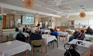 zdjęcie ze spotkania, seniorzy siedzący przy stolikach