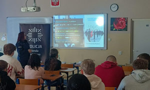 zdjęcie ze spotkania, uczniowie siedzą w ławkach, przed nimi stoją policjanci, trwa prezentacja