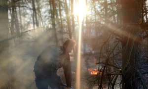 policjant gaszący pożar trawy