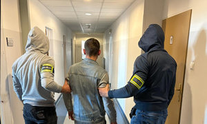 zatrzymany mężczyzna w asyście nieumundurowanych policjantów