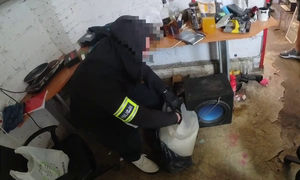 nieumundurowany policjant dokonujący przeszukania pomieszczeń gospodarczych