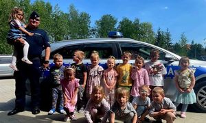 zdjęcie grupowe przedszkolaków i policjanta przy radiowozie