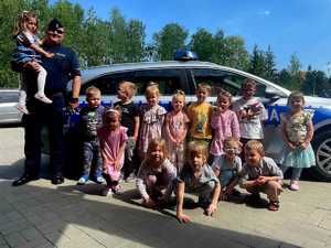 zdjęcie grupowe przedszkolaków i policjanta przy radiowozie