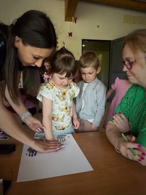 dzieci wspólnie z policjantką robią pamiątkowe odciski dłoni