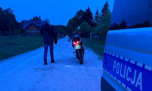 motocyklista zatrzymany do kontroli drogowej, w tle policyjny radiowóz
