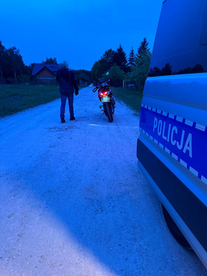 motocyklista zatrzymany do kontroli drogowej, w tle policyjny radiowóz