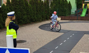 policjanci prowadzą egzamin na kartę rowerową, dzieci pokonują tor przeszkód