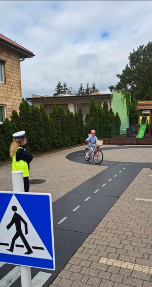 policjanci prowadzą egzamin na kartę rowerową, dzieci pokonują tor przeszkód