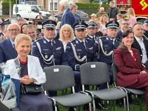 uczestnik pikniku siedzący w radiowozie i trzymający ulotkę zachęcającą do wstąpienia w szeregi policji