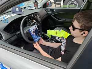 uczestnik pikniku siedzący w radiowozie i trzymający ulotkę zachęcającą do wstąpienia w szeregi policji