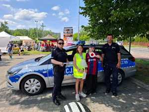 policjanci wspólnie z dziećmi, w tle policyjny radiowóz