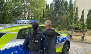 zatrzymany mężczyzna stojący przy policjantce przed radiowozem