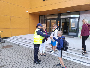 policjantka rozdająca dzieciom odblaski