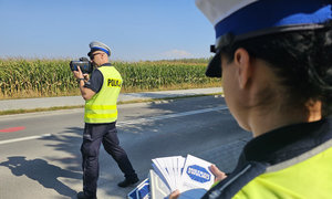 policjanci kontrolujący prędkość, policjantka trzyma ulotki akcji &quot;Mistrzu zwolnij&quot;