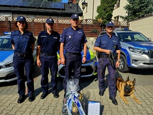 st. asp. Sławomir Matyjasiak wspólnie z psem słuzbowym, w tle radiowóz