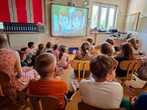 policjant pokazujący dzieciom różnicę widoczności osoby w odblaskach oraz tej która ich nie nosi