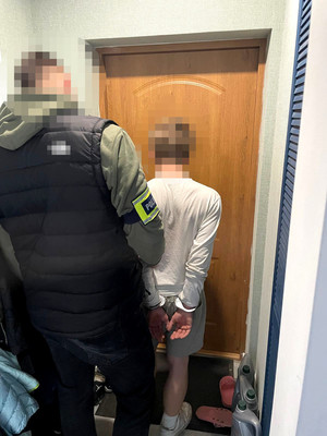 nieumundurowany policjant wraz z zatrzymanym mężczyzną, który ma założone kajdanki na ręce