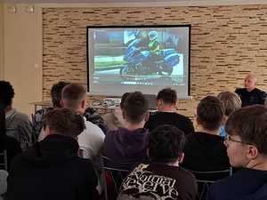 uczniowie siedzą, policjanci omawiają przygotowaną prezentację