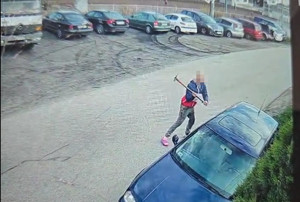 stopklatka  z nagrania, mężczyzna z młotkiem w ręku, niszczy auta