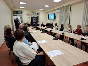 zdjęcie wykonane w trakcie debaty, mieszkańcy siedzą przy stole
