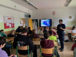 policjantka prowadząca spotkanie z uczniami, w tle wyświetlana jest prezentacja