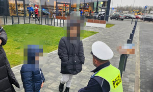 dzieci, a obok nich policjant