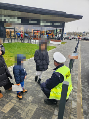 dzieci, a obok nich policjant