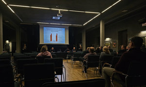 zdjęcie wykonane w trakcie debaty społecznej, na wyświetlaczu pokazywane są slajdy dot. bezpieczeństwa, zgromadzeni mieszkańcy siedzą w sali kinowej