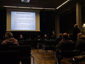 zdjęcie wykonane w trakcie debaty społecznej, na wyświetlaczu pokazywane są slajdy dot. bezpieczeństwa, zgromadzeni mieszkańcy siedzą w sali kinowej