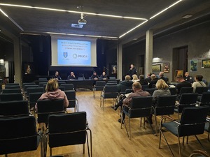 zdjęcie wykonane w trakcie debaty społecznej, na wyświetlaczu pokazywane są slajdy dot. bezpieczeństwa, zgromadzeni mieszkańcy siedzą w sali kinowej