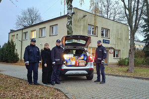 policjanci stojący przy radiowozie, w bagażniku produkty zebrane w ramach szlachetnej paczki